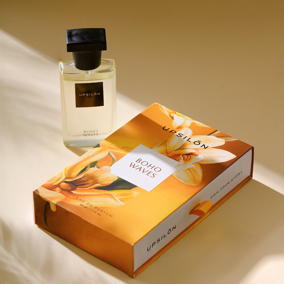 bottle of "Boho Waves" Eau de Parfum by UPSILON resting elegantly on a wooden table beside a box